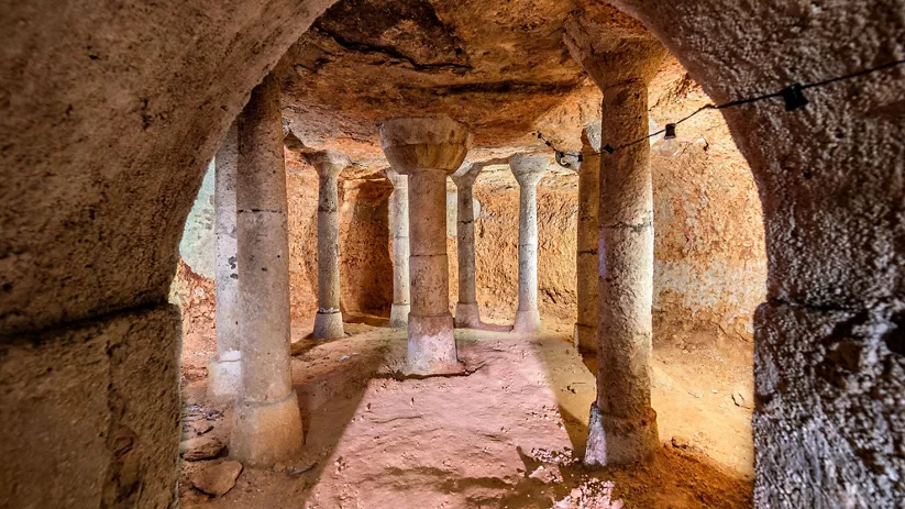 Interior de una cueva con columnas talladas en la piedra.