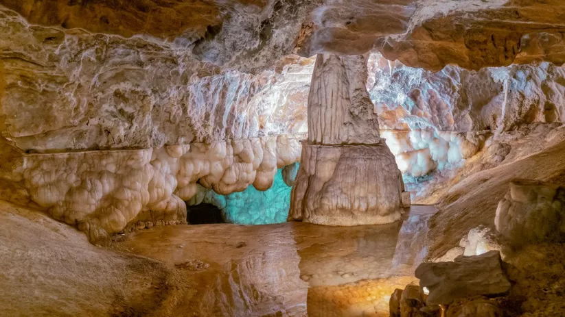 Interior de cueva con estalactitas y formaciones calcáreas iluminadas.