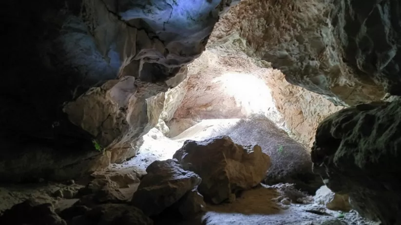 Entrada iluminada de cueva entre rocas