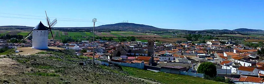Vista panorámica de un pueblo con molino de viento en una colina.