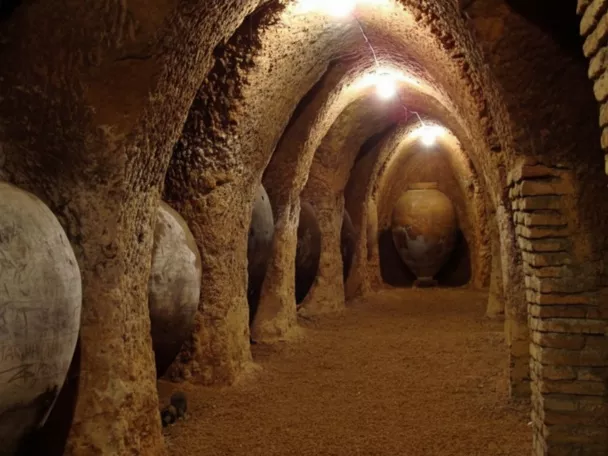 Galería subterránea con tinajas de barro bajo arcos.