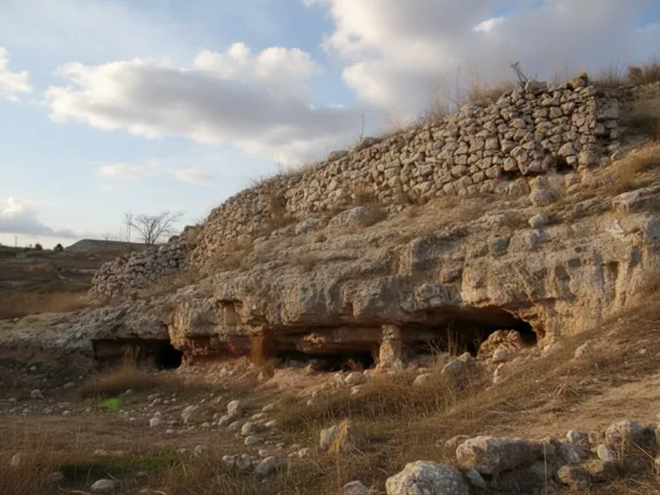 Viviendas excavadas en roca junto a muralla de piedra