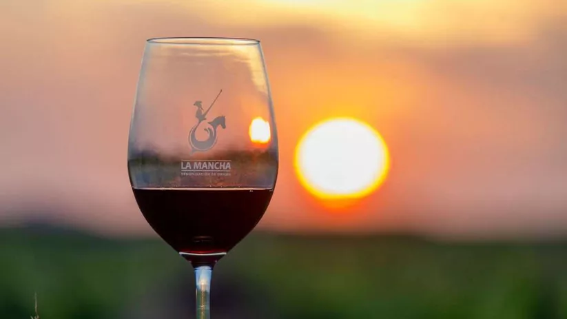 Copa de vino tinto con atardecer en el viñedo