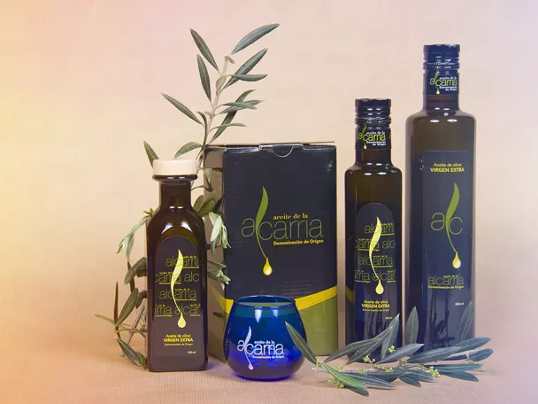 Botellas y envases de aceite de oliva virgen extra junto a ramas de olivo