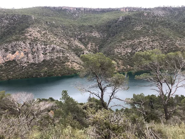 Embalse rodeado de laderas verdes y vegetación mediterránea