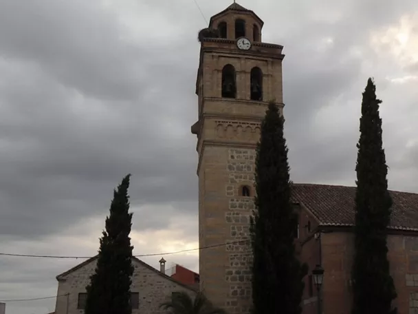 Iglesia de piedra con torre campanario bajo cielo nublado