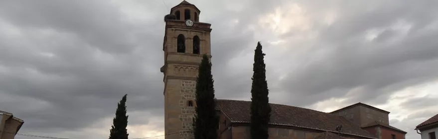 Iglesia de piedra con torre campanario bajo cielo nublado