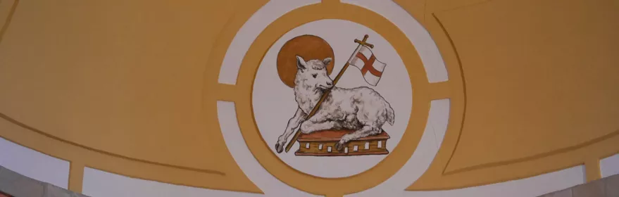 Pintura mural con cordero y símbolo religioso.