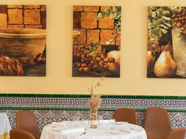 Salón con mesas redondas y cuadros decorativos en pared amarilla