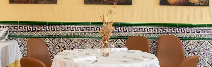 Salón con mesas redondas y cuadros decorativos en pared amarilla