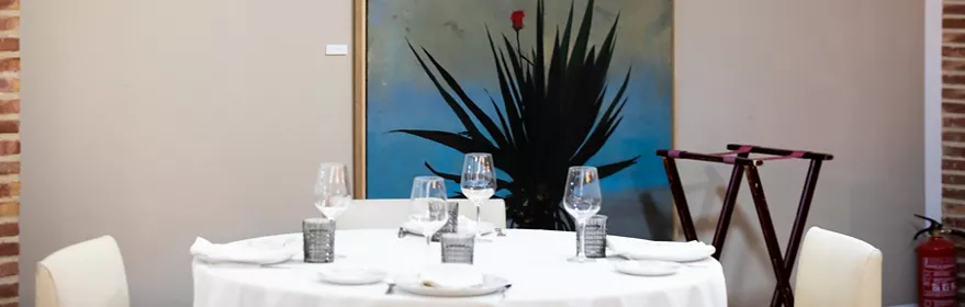 Mesa redonda con mantelería blanca y gran cuadro