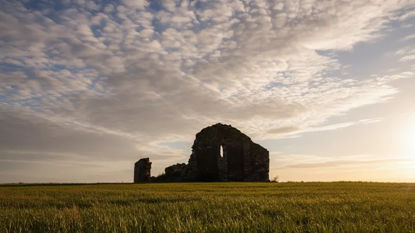 Ruinas históricas en campo abierto bajo cielo nuboso