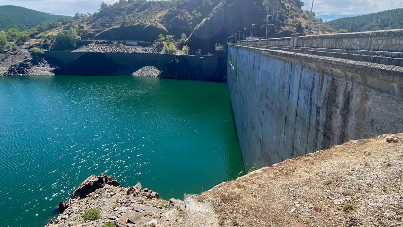 Muro de presa sobre aguas turquesas.