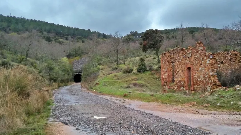Vía verde con túnel excavado en la montaña y ruinas de piedra