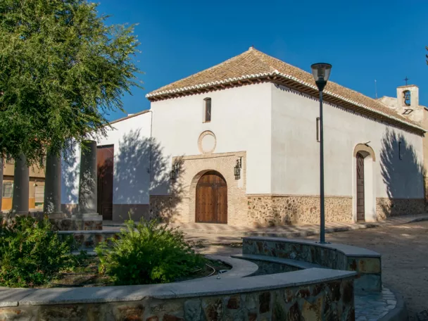 Iglesia blanca junto a plaza con jardín y farola