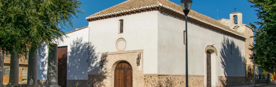 Iglesia blanca junto a plaza con jardín y farola