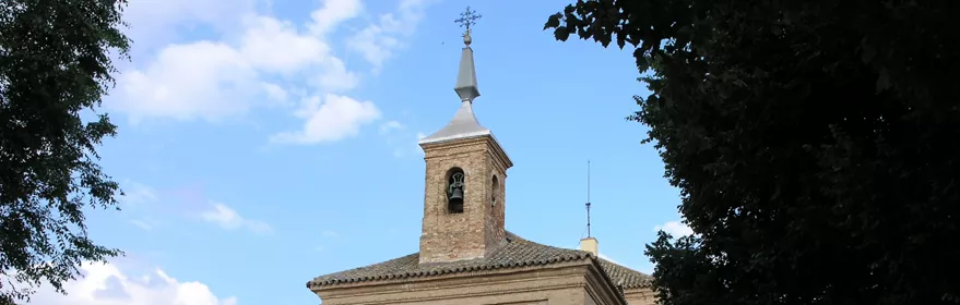 Iglesia de piedra en plaza con árboles