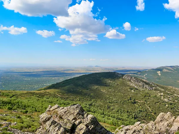 Vista panorámica de valle verde con pueblo al fondo y montañas.