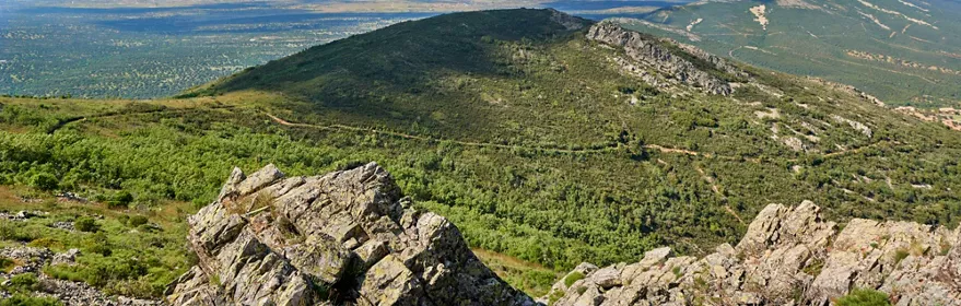 Vista panorámica de valle verde con pueblo al fondo y montañas.
