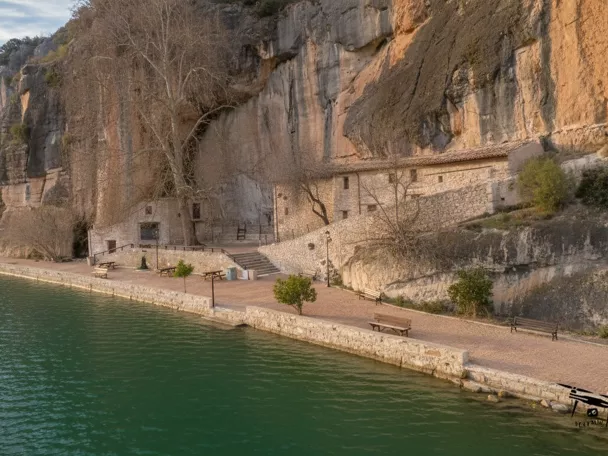 Ermita junto al agua bajo acantilado rocoso