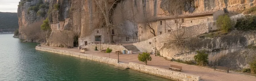 Ermita junto al agua bajo acantilado rocoso