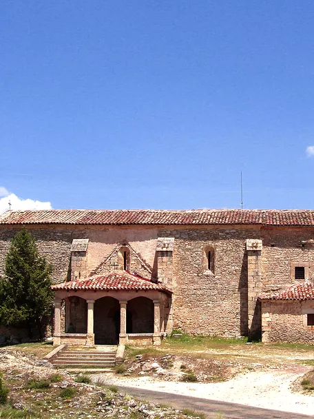 Iglesia de piedra con torre y pórtico.