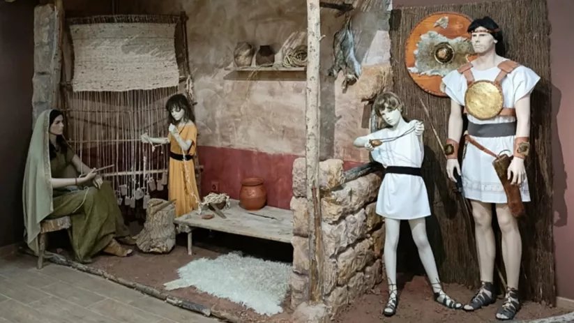 Escena doméstica antigua con telar, choza y figuras humanas