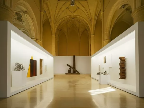 Sala contemporánea dentro de iglesia gótica con paneles blancos.