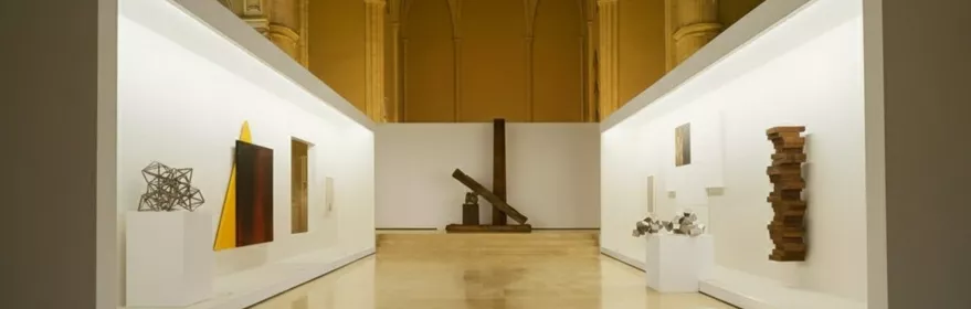 Sala contemporánea dentro de iglesia gótica con paneles blancos.