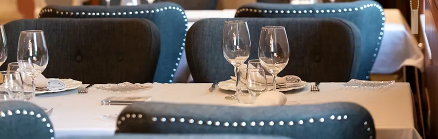 Salón elegante con mesas vestidas y sillones tapizados