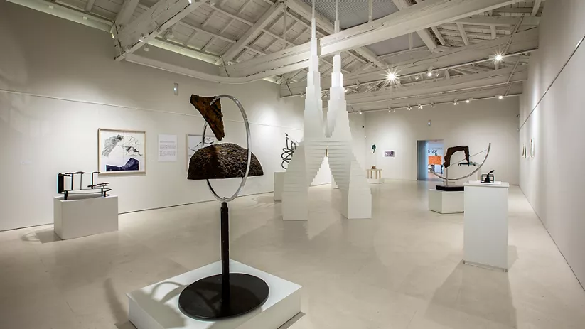Sala blanca con esculturas y techos de madera.