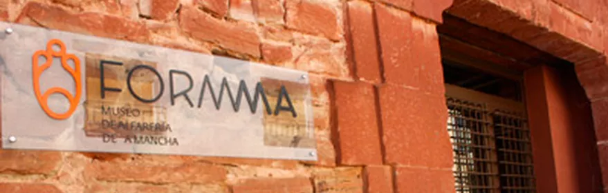 Cartel de museo sobre muro de piedra con puerta de entrada