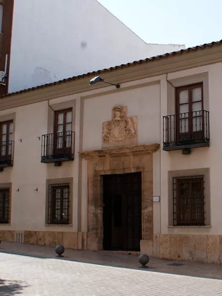Fachada blanca con balcón y portada de piedra