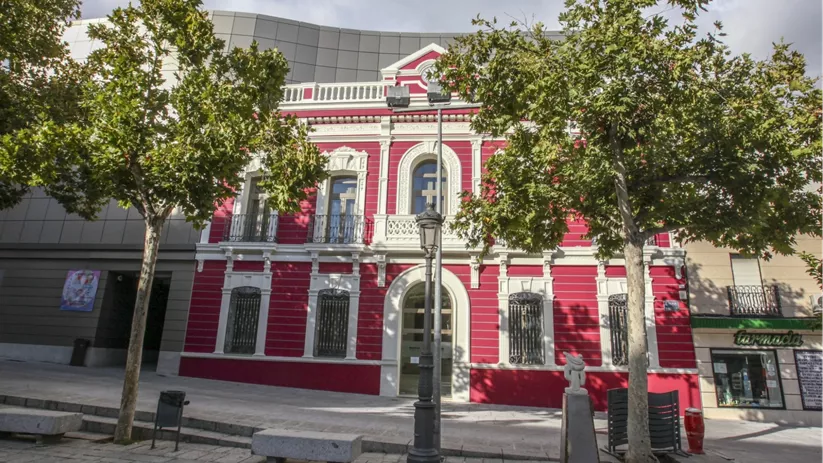 Fachada de edificio histórico restaurado junto a una plaza arbolada