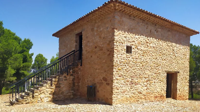 Edificio de piedra con escalera exterior y cubierta a cuatro aguas