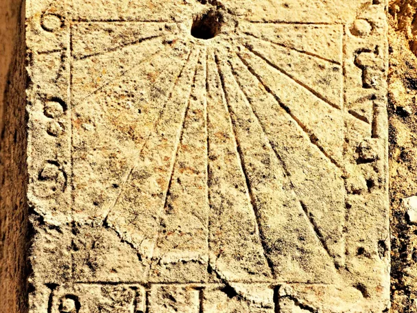 Reloj de sol grabado en piedra en fachada histórica