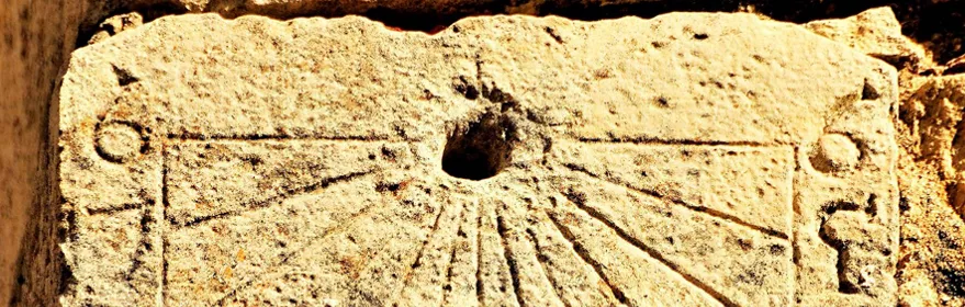 Reloj de sol grabado en piedra en fachada histórica
