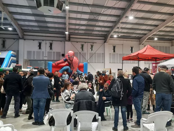 Público en feria de cómic en pabellón cubierto con figuras y puestos temáticos.