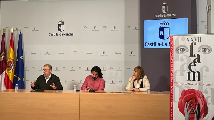 Mesa de presentación con ponentes sentados ante fondo institucional y carteles.