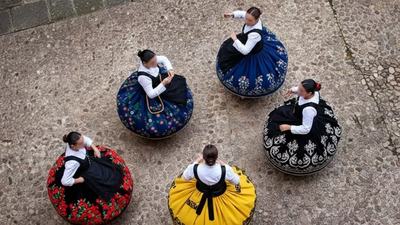Vista cenital de bailarinas con faldas amplias y coloridas sobre suelo empedrado.