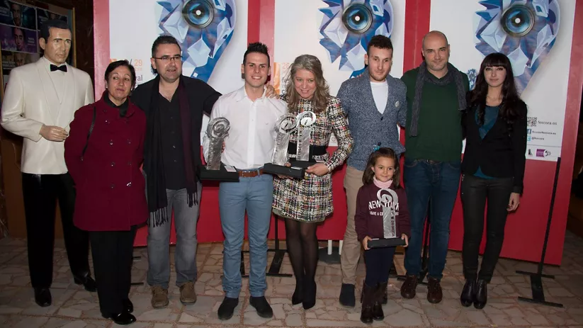 Grupo con premios posando ante panel del festival