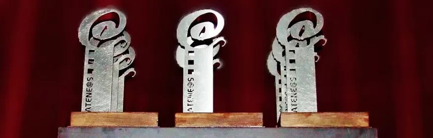 Trofeos plateados sobre mesa ante cortina roja