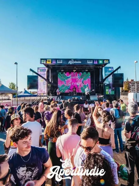 Público numeroso frente a un escenario al aire libre durante un concierto diurno.