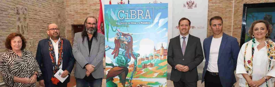 Seis personas posan junto a un cartel de festival en un patio interior