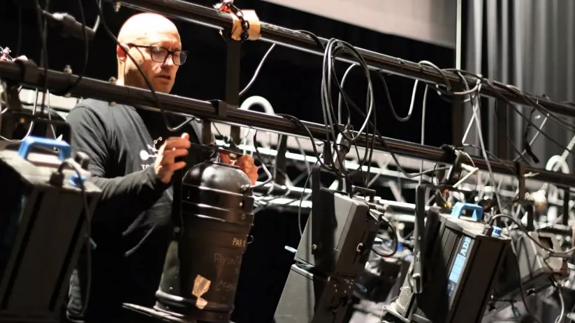 Técnico ajustando iluminación en sala de cine.