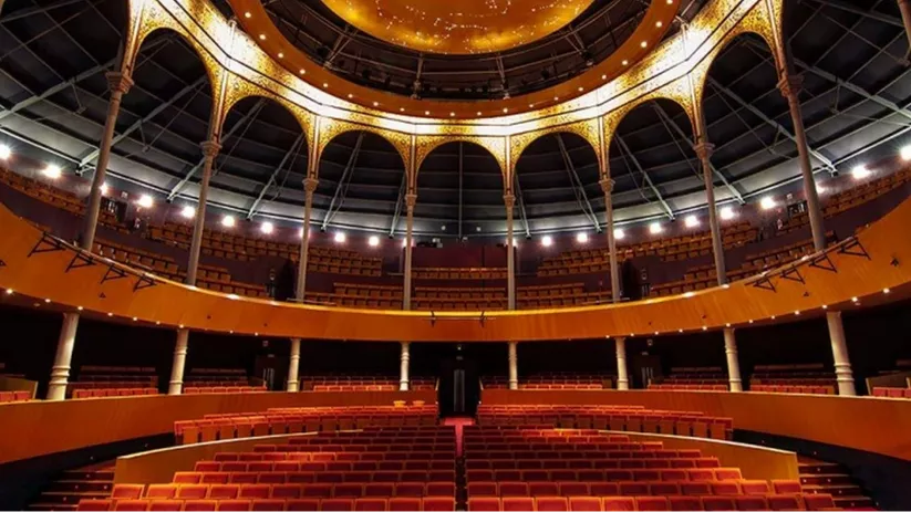 Interior de teatro histórico con cúpula decorada y platea vacía.