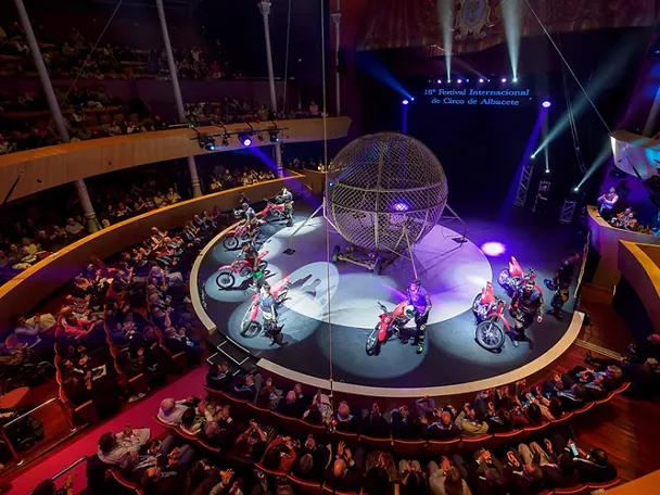 Espectáculo circense con motoristas girando dentro de una esfera metálica ante público