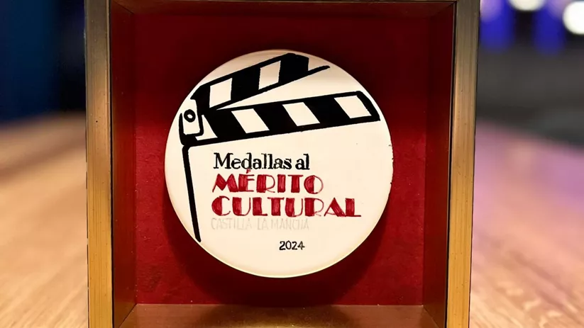 Medalla cultural en vitrina sobre mesa de madera