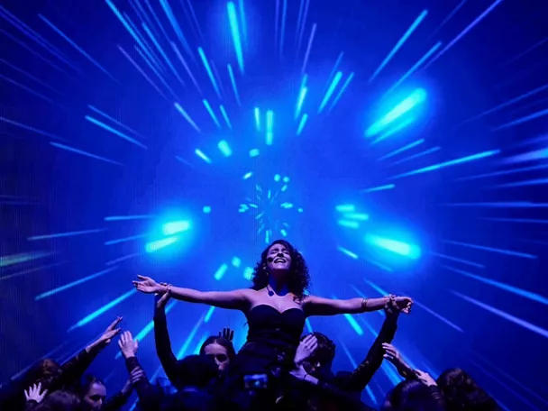 Actriz alzada en escena con luces azules de fondo