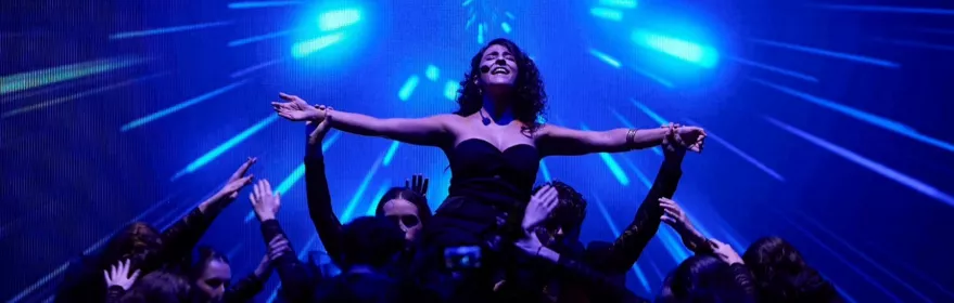 Actriz alzada en escena con luces azules de fondo